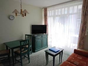 ein Wohnzimmer mit Fernseher und Tisch mit Stühlen in der Unterkunft Fewo Rosenhof 02 in Kühlungsborn