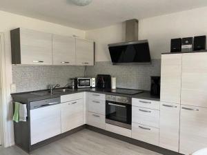 a kitchen with white cabinets and a microwave at Bungalow "Sonnenschein" in Wustrow