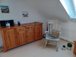 a room with a chair and a wooden cabinet at Ferienwohnung Maren Graf in Neustadt in Holstein +5 photos
