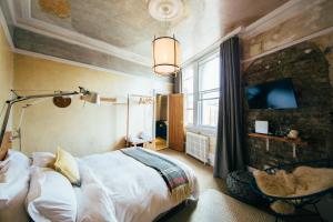 a bedroom with a bed and a tv on a wall at The Culpeper Bedrooms in London