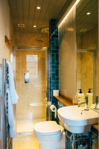 a bathroom with a toilet and a sink and a shower at The Culpeper Bedrooms in London