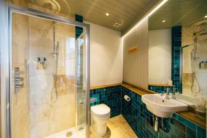 a bathroom with a shower and a toilet and a sink at The Culpeper Bedrooms in London