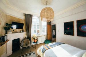 a bedroom with a bed and a fireplace and a chandelier at The Culpeper Bedrooms in London