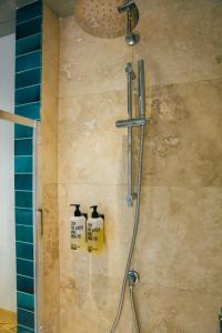 a shower with two soap dispensers in a bathroom at The Culpeper Bedrooms in London