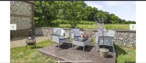 a patio with chairs and a table and a stone wall at The Ducks - Stunning remote Norfolk Appt with Lazy Spa in Mileham