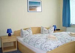 a bedroom with a bed and a night stand with a blue lamp at Haus Dornröschen in Koserow