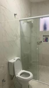 a bathroom with a toilet and a glass shower at Casa Piscina Guaratuba 400mt praia in Guaratuba