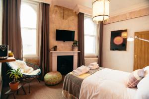 a bedroom with a bed and a fireplace and a tv at The Culpeper Bedrooms in London