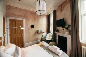 a bedroom with a bed and a fireplace and a chandelier at The Culpeper Bedrooms in London