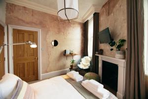 a bedroom with a bed and a fireplace at The Culpeper Bedrooms in London