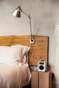 a bed with a lamp and a clock on a night stand at The Culpeper Bedrooms in London