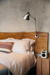 a bed with a lamp and a clock on a table at The Culpeper Bedrooms in London