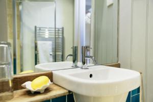 a bathroom with a white sink and a mirror at The Culpeper Bedrooms in London