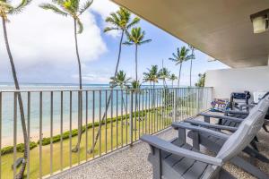 a balcony with chairs and palm trees and the ocean at Amazing Beachfront Condo with AC in Laie