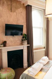 a living room with a fireplace with a television on a wall at The Culpeper Bedrooms in London