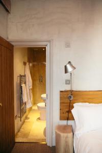 a bedroom with a bed and a bathroom with a toilet at The Culpeper Bedrooms in London
