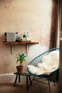 a room with a chair and a shelf and a plant at The Culpeper Bedrooms in London