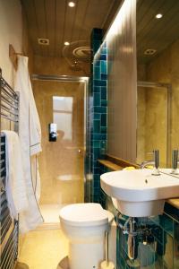 a bathroom with a sink and a toilet and a shower at The Culpeper Bedrooms in London