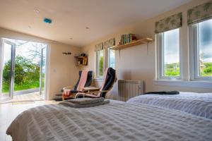 a bedroom with two beds and two chairs and windows at The Drey Inchberry 