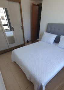a white bed in a room with a mirror at Apto condomínio conforto e ótima localização in Lucas do Rio Verde