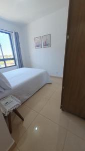 a white bedroom with a bed and a window at Apto condomínio conforto e ótima localização in Lucas do Rio Verde