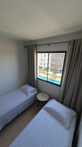a small room with two beds and a window at Apto condomínio conforto e ótima localização in Lucas do Rio Verde