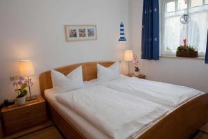 ein Bett mit weißen Laken und Kissen in einem Schlafzimmer in der Unterkunft Fewo Rosenhof 03 in Kühlungsborn + 8 Fotos
