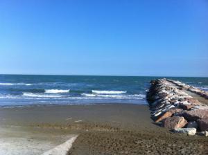 a beach with a rock wall and the ocean at Hotel Berna in Eraclea Mare