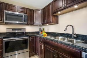 a kitchen with wooden cabinets and a stainless steel sink at Kalanikai 306 in Kailua-Kona