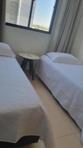 a bedroom with two beds and a table and a window at Apto condomínio conforto e ótima localização in Lucas do Rio Verde