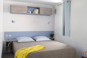 a bedroom with a bed with a yellow blanket on it at Camping Rouffignac-St-Cernin in Ladeymarie
