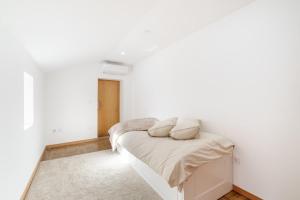 a white bedroom with a bed with two pillows on it at Casa de Lamalonga T2 in Campos