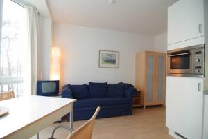 ein Wohnzimmer mit einer blauen Couch und einer Küche in der Unterkunft Villa Strandperle, Whg. 10 in Bansin