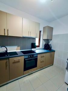 a kitchen with wooden cabinets and a stove top oven at Pensiunea Silva Dobra in Şugag