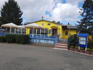 una casa amarilla con una valla azul delante de ella en Kleiner Bungalow Wiesenperle, en Trassenheide