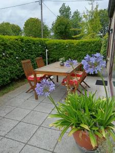 einen Holztisch mit zwei Stühlen und lila Blumen in der Unterkunft Michael, Vakantiehuisje aan zee in De Haan