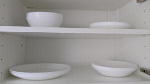 two white bowls sitting on shelves in a kitchen at Magaslak Apartman in Kaposvár +17 photos