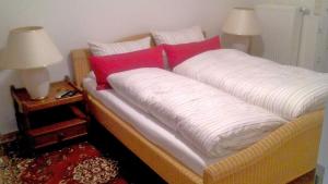 a bed with white and red pillows and two lamps at Ferienhaus "Buchholz" in Buchholz +3 photos
