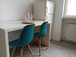 Una cocina con dos sillas azules en un mostrador con un refrigerador. en Lena, en Gdansk 5 fotos más