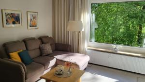 a living room with a couch and a large window at Kurpark Appartement in Glücksburg +6 photos