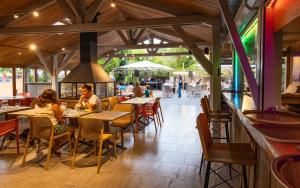 a group of people sitting at tables in a restaurant at Camping Tamniès in Tamniès