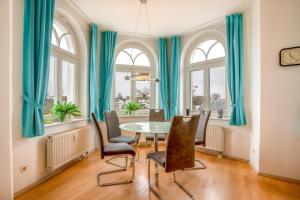 a dining room with blue curtains and a table and chairs at Ferienwohnung 10 Haus Metropol in Binz