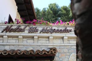 ein Schild für ein kleines Albuquerque an der Wand mit Blumen in der Unterkunft Hotel Vila Aleksander in Berat