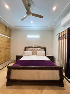 Un dormitorio con una cama y un ventilador de techo. en Modern 3-Bed Retreat E11 PEACEFUL, en Islamabad
