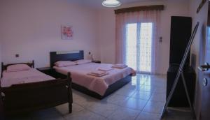 een slaapkamer met twee bedden en een groot raam bij vickys family house in Stavros
