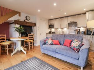 a living room with a blue couch and a kitchen at The Farmhouse Kitchen in Ripon