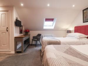 a bedroom with two beds and a desk and a window at The Farmhouse Kitchen in Ripon