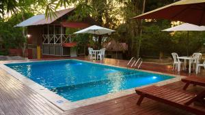 a swimming pool with tables and chairs and umbrellas at Chaikoni Lodge in Pucallpa