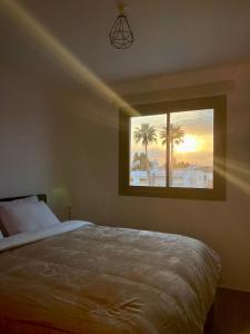 a bedroom with a bed and a window with palm trees at Modern Designer Home in Larnaka