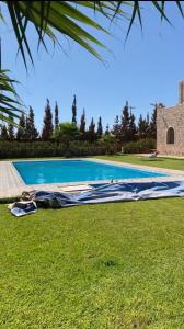 a mattress on the grass next to a swimming pool at Villa zaytoun in Agadir